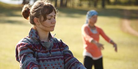 Zwei Frauen üben Qi Gong auf einer Wiese