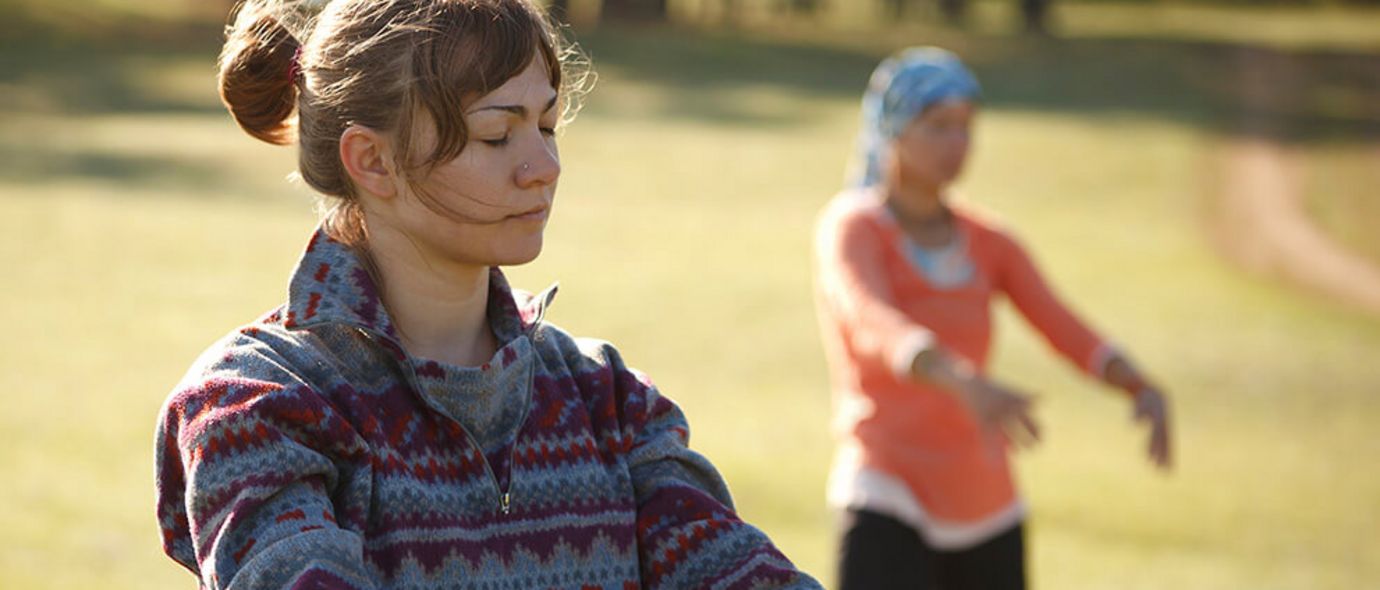 Zwei Frauen üben Qi Gong auf einer Wiese