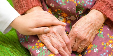  Eine Ärztin legt ihre Hand auf die einer älteren Frau