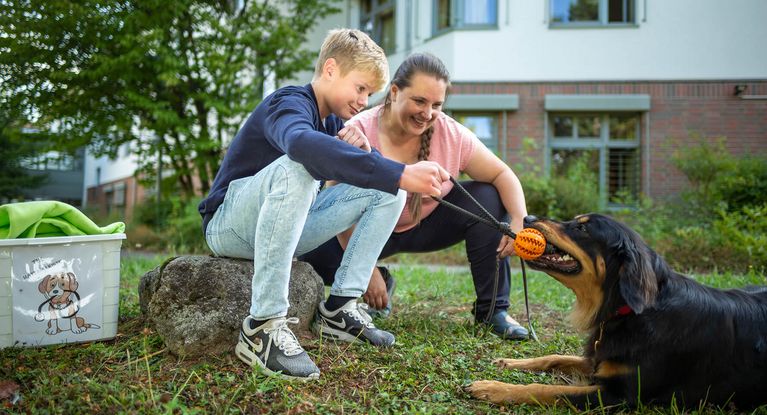 Therapiehund Ein Junge und eine Therapeutin spielen mit dem Therapiehund