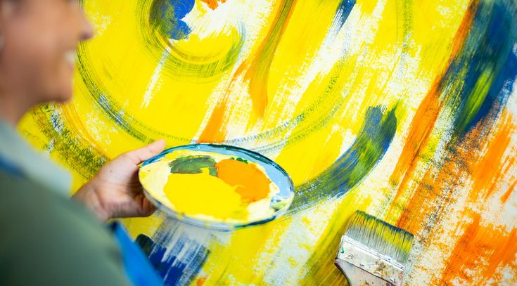 In der Kunsttherapie malt eine Patientin helle Farben auf eine große Fläche
