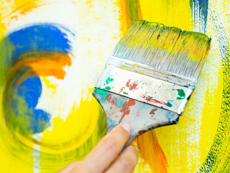 In der Kunsttherapie malt eine Patientin helle Farben auf eine große Fläche