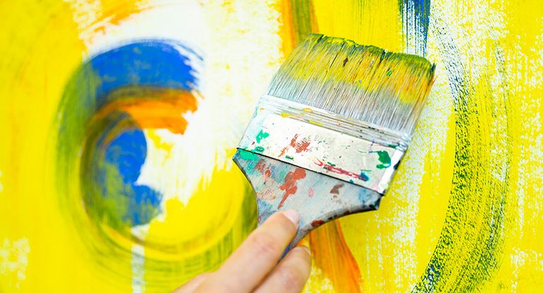 In der Kunsttherapie malt eine Patientin helle Farben auf eine große Fläche