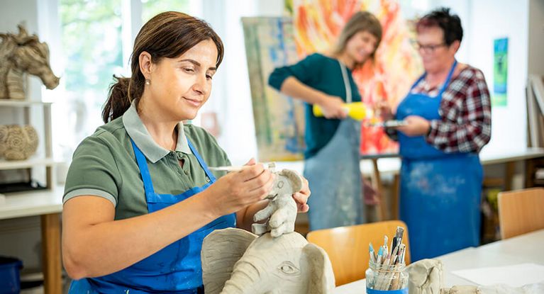 Eine Patientin töpfert einen kleinen Elefanten bei der Kunsttherapie