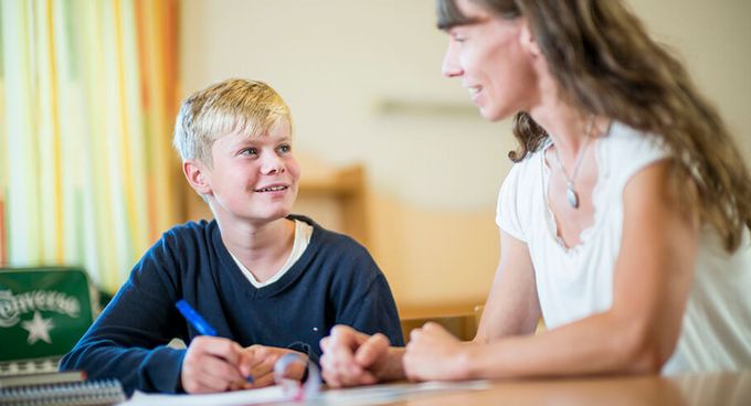 Ein Junge macht lernt mit einer Frau in der Hausaufgabenbetreuung